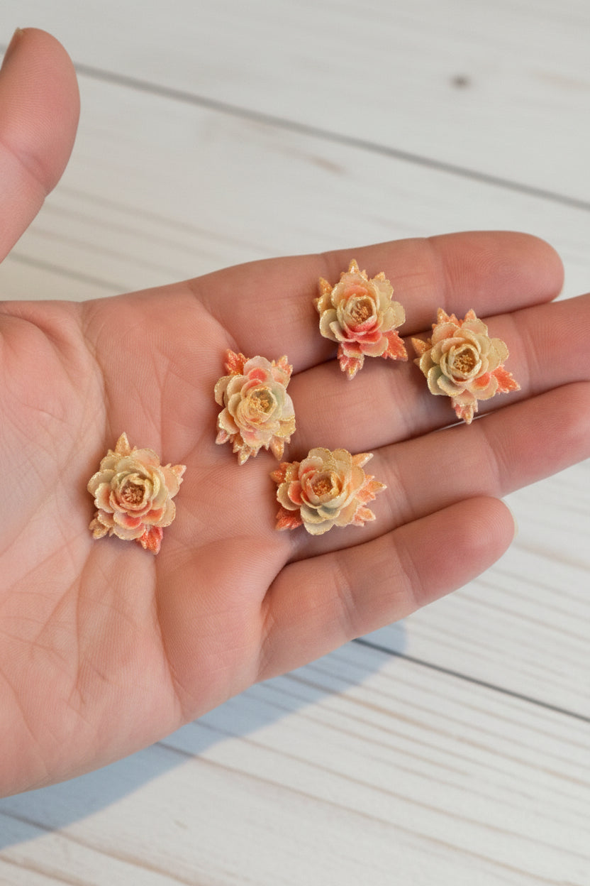 Small soft blue fabric flowers with green leaves held in a hand to show size, craft embellishments pack of 50
