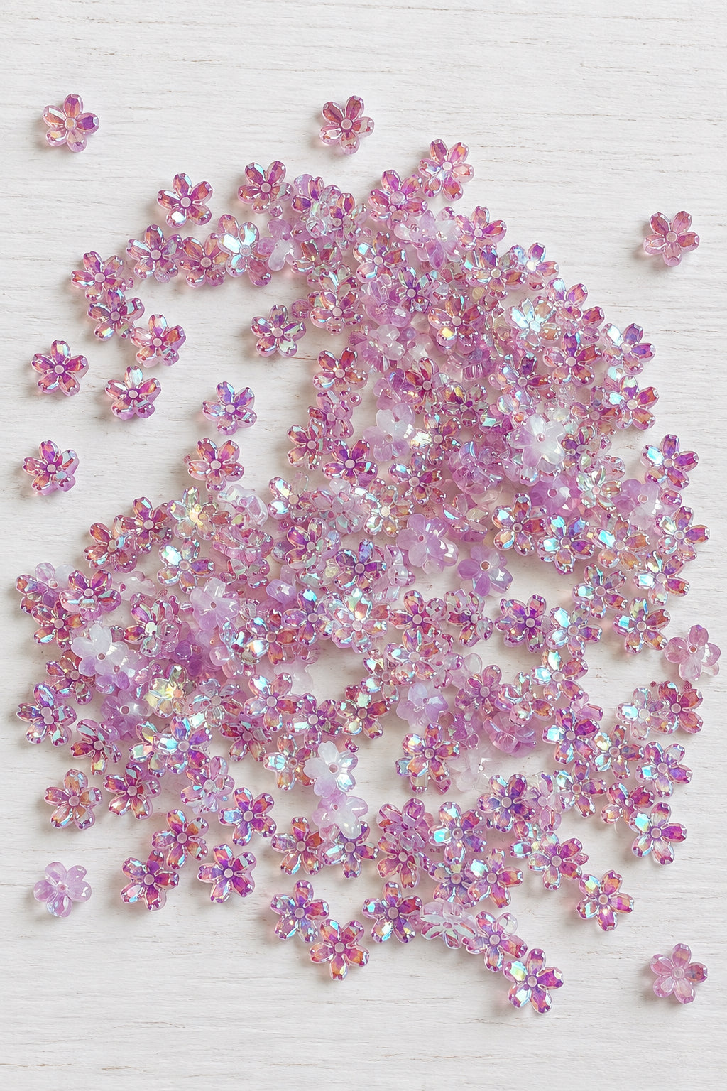 Five-petal glass sakura flower beads with an iridescent finish for jewellery-making and craft projects. ⠋