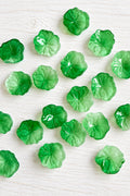 Green glass lily pad beads with translucent colouring, textured leaf details and scalloped edges.