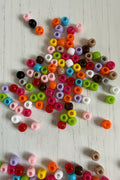 8mm mixed colour acrylic pony beads with large holes scattered on a white wooden surface, 10g pack for jewellery and craft making
