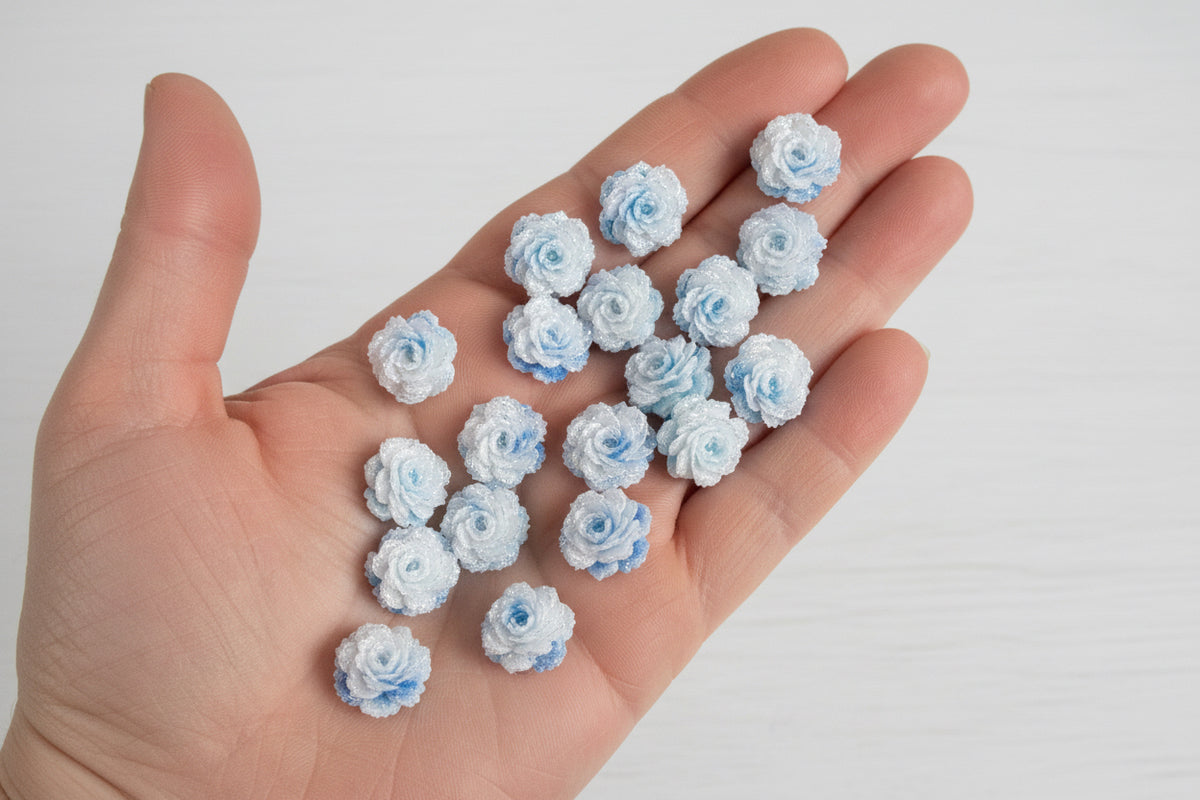 14mm white and blue soft rose flower embellishments held in a hand to show size, pack of 50 for crafts