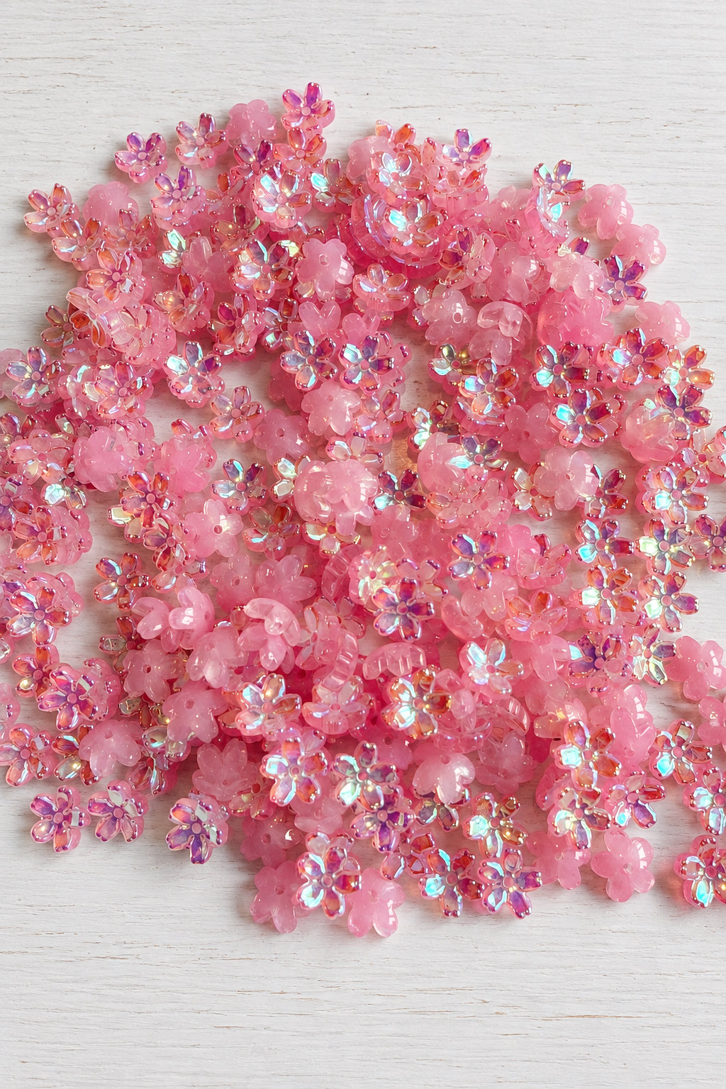 Five-petal glass sakura flower beads with an iridescent finish for jewellery-making and craft projects. ⠋
